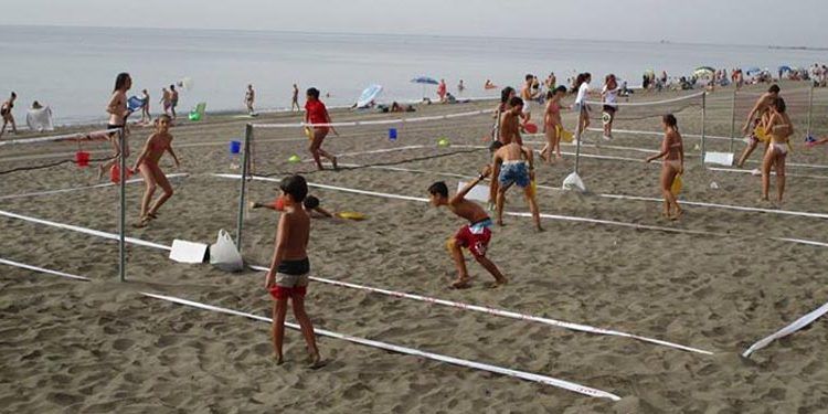 niñas y niños juegan al bádminton en la playa